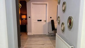 A hallway with a patterned carpet, a white door, and decorative wall sconces. - 1 Bed Flat - Sleeps 2 - Jacuzzi - Parking - Wifi (Birmingham)