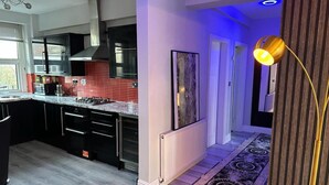 A modern kitchen with black cabinets, a red backsplash, and a marble countertop. - 1 Bed Flat - Sleeps 2 - Jacuzzi - Parking - Wifi (Birmingham)