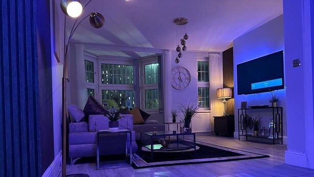A modern living room with a sofa, coffee table, and TV. - 1 Bed Flat - Sleeps 2 - Jacuzzi - Parking - Wifi (Birmingham)