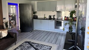 Una cocina moderna con gabinetes grises, encimera negra y electrodomésticos de acero inoxidable.