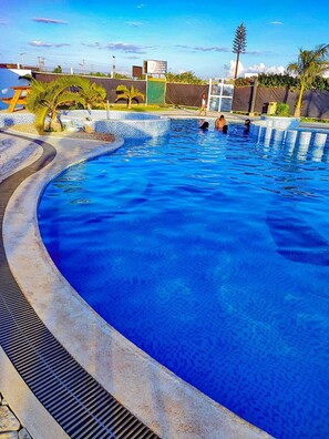 A swimming pool with a tiled edge, a metal ladder, and a palm tree. - Lux Suites Tatu City Vacation House (Ruiru)