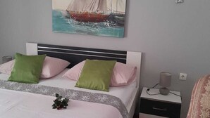 Un dormitorio con una cama, almohadas, una mesita de noche, una lámpara y una silla.