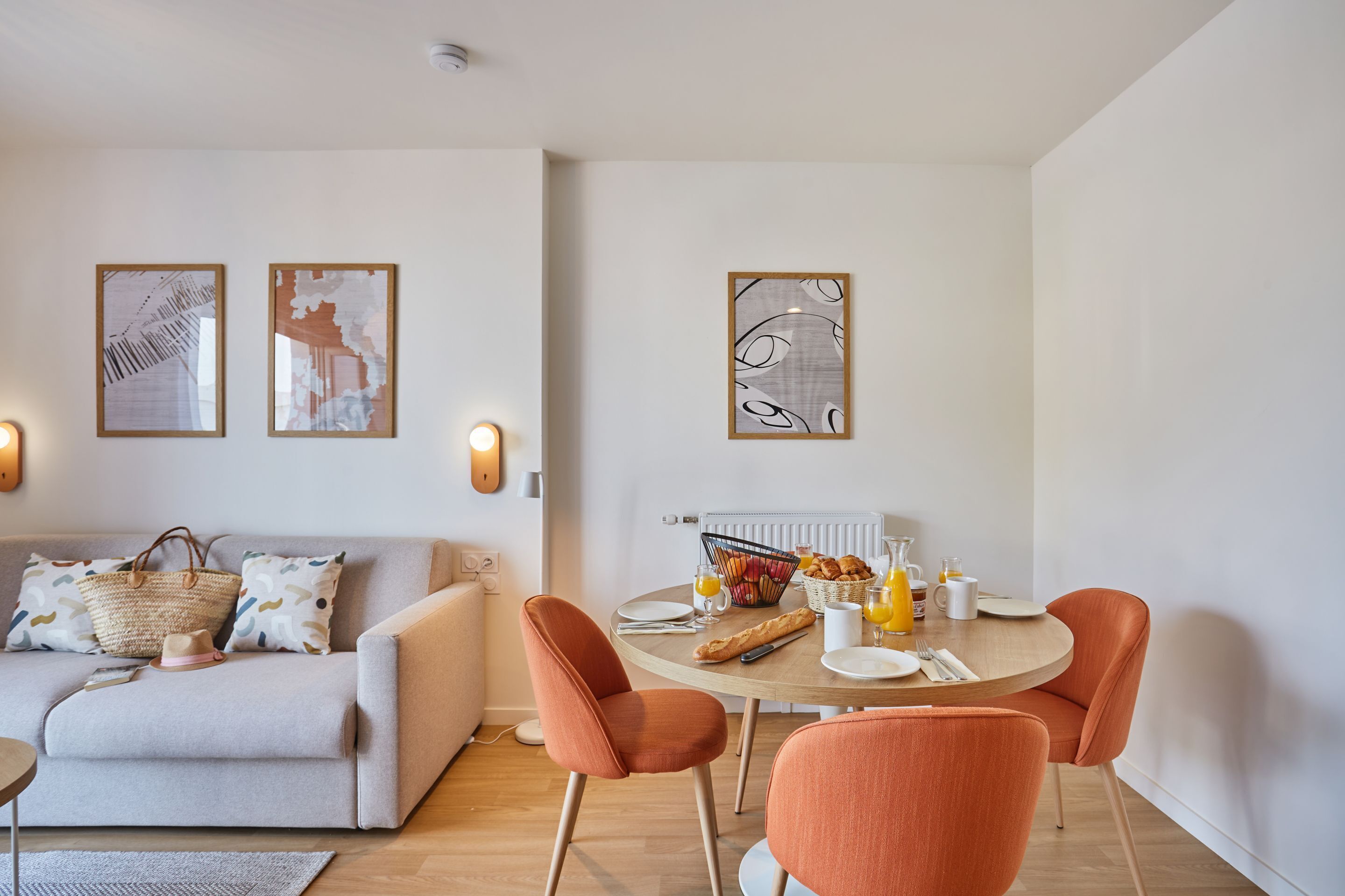 Ein modernes Wohnzimmer mit einer Couch, einem Esstisch mit Stühlen und Wandbildern.