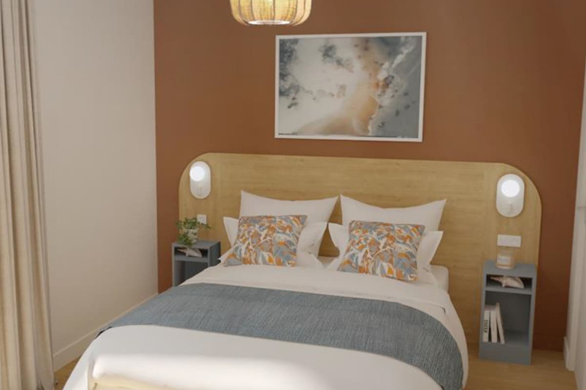 A neatly arranged bedroom with a bed, a bedside table, a nightstand, and a wall-mounted lamp.