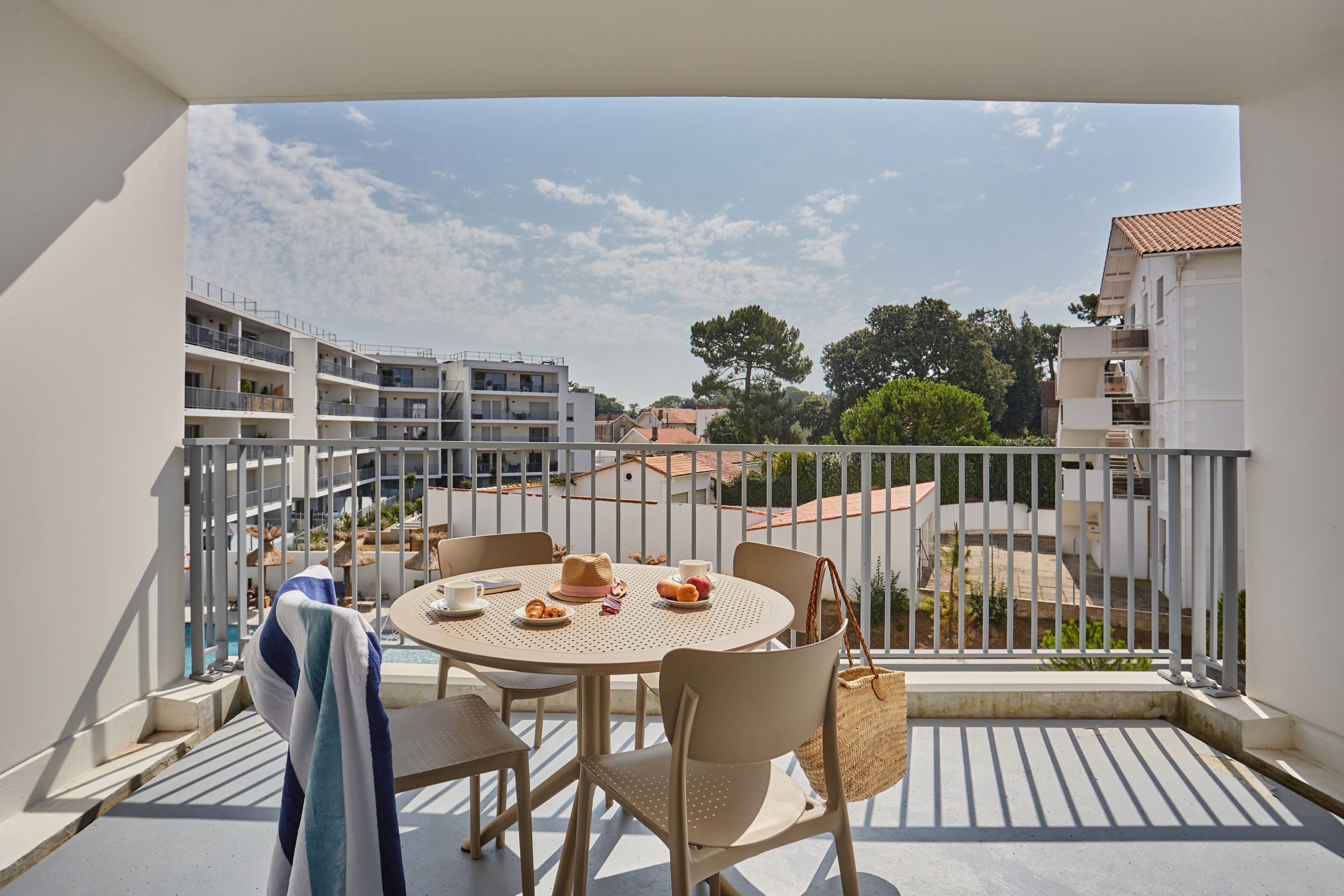 Ein Balkon mit rundem Tisch, Stühlen und Blick auf die umliegenden Gebäude.