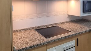 A kitchen with white cabinets, a granite countertop, a built-in oven, and a microwave.