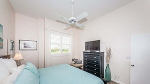 A bedroom with a bed, a dresser, a television, a ceiling fan, and a door. - VVN 5-229 - Vista Verde North - Premium (St. Petersburg)
