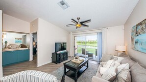 A living room with a sofa, a coffee table, a TV, and a ceiling fan. - VVN 5-229 - Vista Verde North - Premium (St. Petersburg)