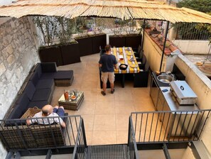 Een terras buiten met een eettafel, zitplaatsen en een barbecuehoek.