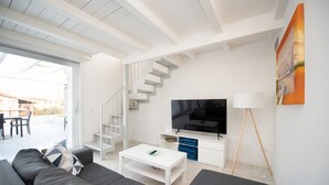 Un salon moderne avec un canapé, un téléviseur et un escalier.