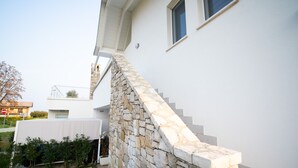 Une maison moderne avec un escalier en pierre menant à une porte blanche.