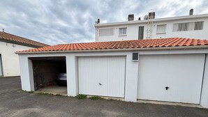 Un bâtiment d’un seul étage, doté d’un garage, dans lequel une voiture est garée, et surmonté d’un toit recouvert de tuiles rouges.