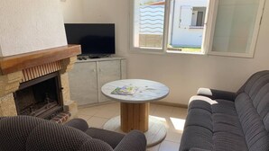 Ein gemütliches Wohnzimmer mit Kamin, Fernseher und einem runden Tisch mit Zeitschriften.