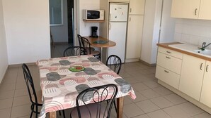 Eine kompakte Küche mit Esstisch, Stühlen, einer Mikrowelle, einem Kühlschrank und einem Spülbecken.