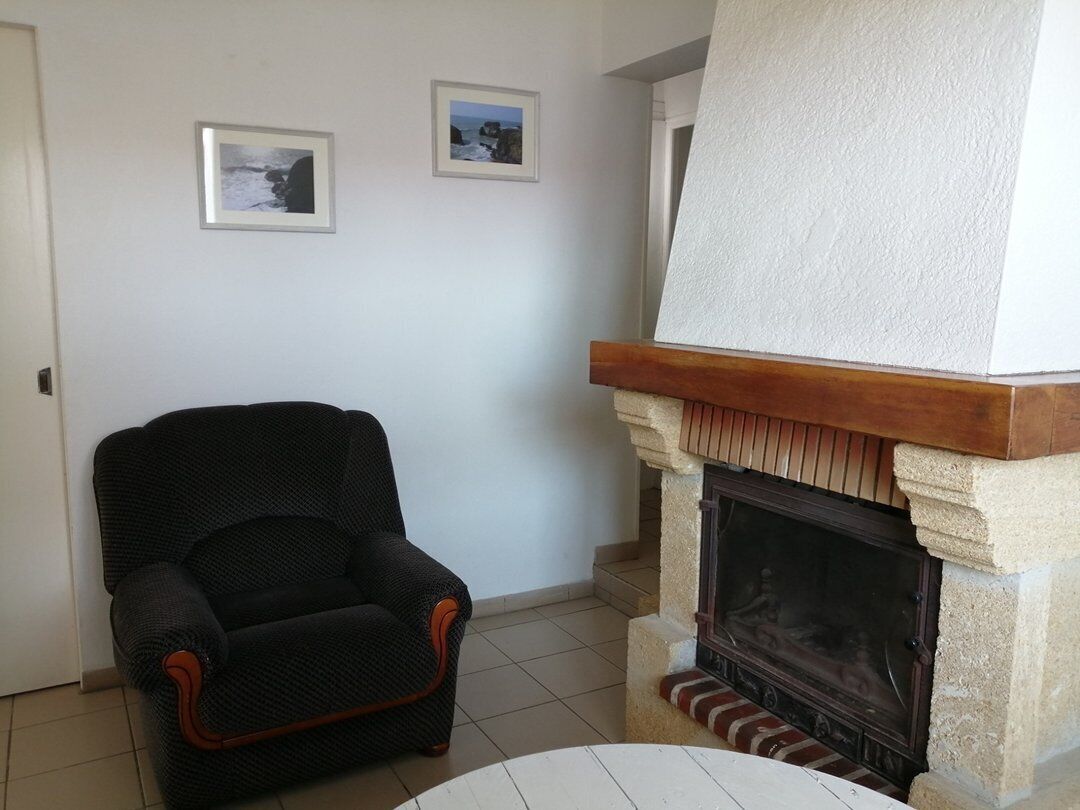 A living room with a fireplace, a black armchair, and two framed pictures on the wall.