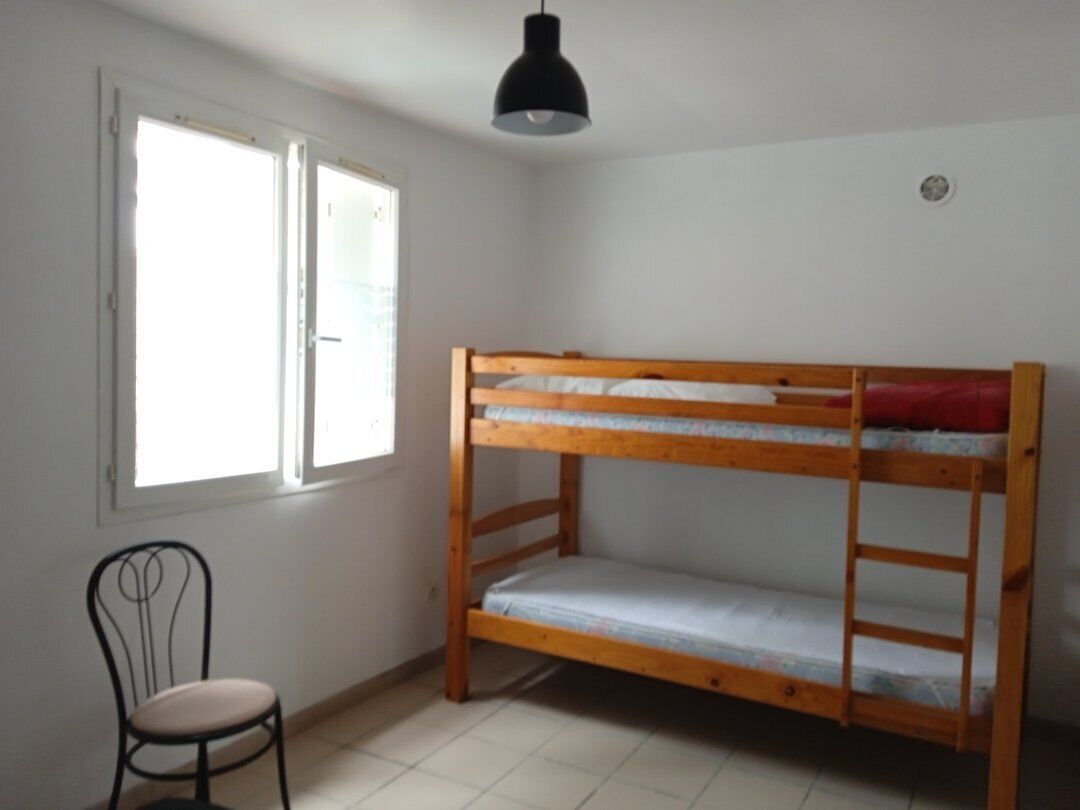 Een stapelbed in een kamer met een stoel en een raam.