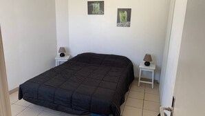 Ein Schlafzimmer mit einem großen Bett, zwei Nachttischen mit Lampen und zwei gerahmten Bildern an der Wand.