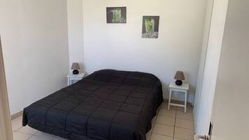 Une chambre avec un grand lit, deux tables de chevet avec des lampes et deux tableaux encadrés accrochés au mur.