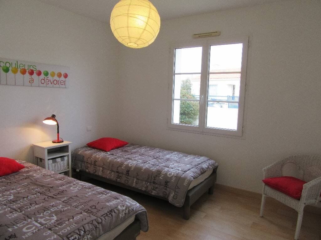 Een kamer met twee bedden, een stoel, een lamp en een raam.