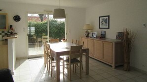 A dining area with a table and chairs, a cabinet, a lamp, and a clock on the wall.