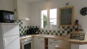 A compact kitchen with a refrigerator, stove, oven, and a window providing natural light.