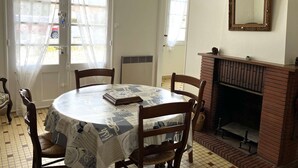A dining room with a round table, chairs, a fireplace, and a large mirror on the wall. - La tranquille - St Hilaire de Riez (SAINT HILAIRE DE RIEZ)