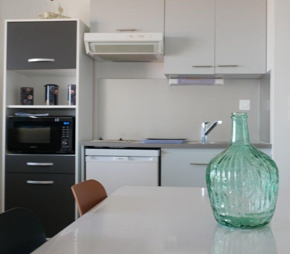 Een koelkast, een broodrooster, kookgerei, borden en bestek