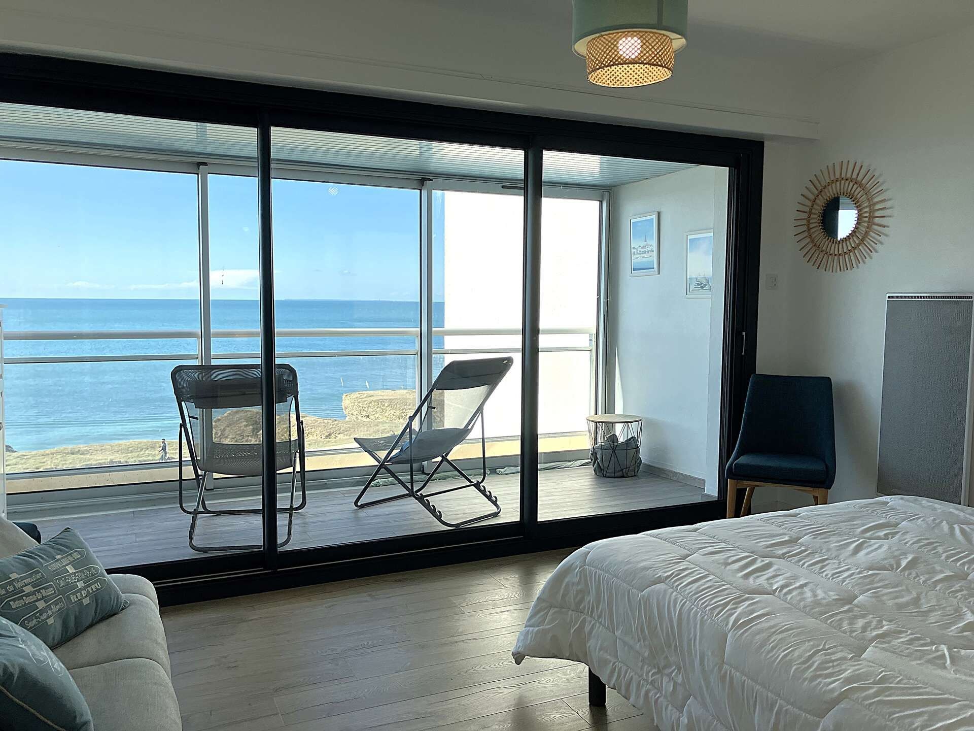 Une chambre dotée d’une grande porte-fenêtre coulissante donnant sur un balcon avec vue sur la mer.