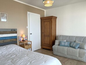 Une chambre à coucher comprenant un lit, une table de chevet, une armoire et un canapé.