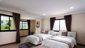 Habitación de hotel con dos camas, un ventanal con cortinas y una pintura en la pared, con vista a zonas verdes.