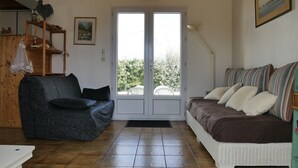 A living room with a sofa, a chair, a table, and a door leading to an outdoor area.