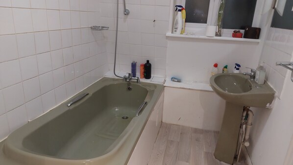 A bathroom with a bathtub, a sink, and various toiletries on the countertop.