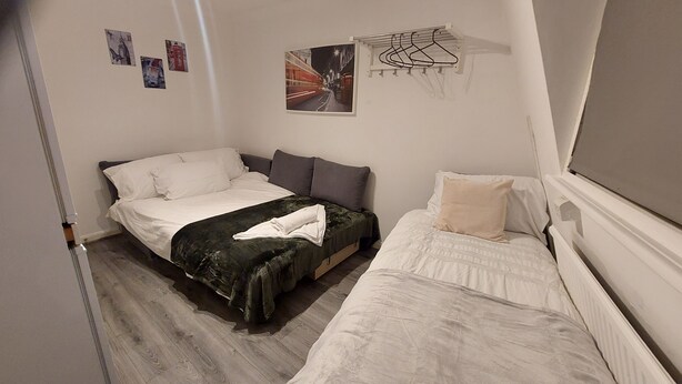 A small, neatly arranged bedroom with two single beds, a small table, and a wall-mounted drying rack. - 2-bed Apartment Sleeps 7 With Wi-fi (London)