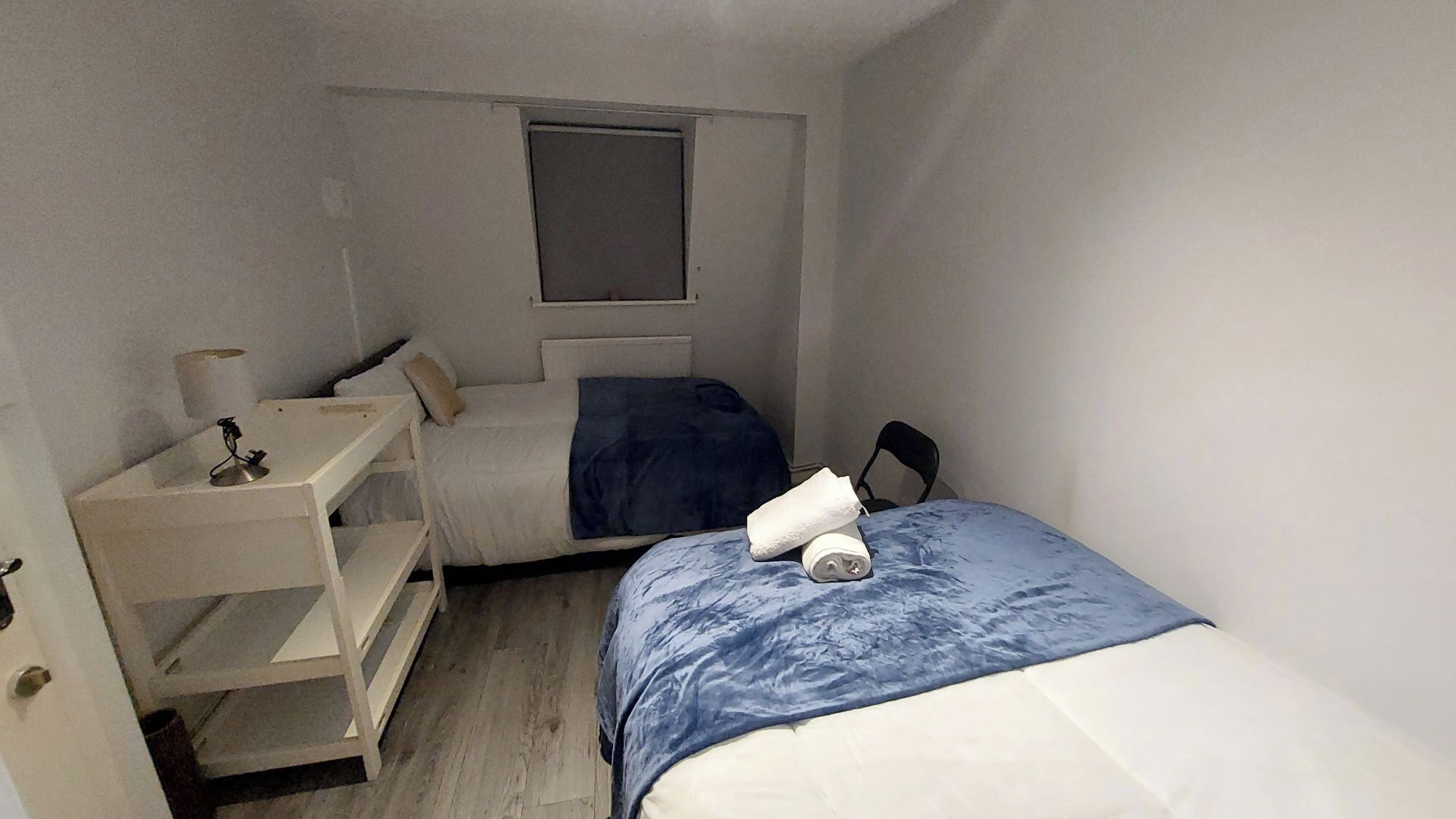 A small, compact room with a bed, a desk, and a chair.