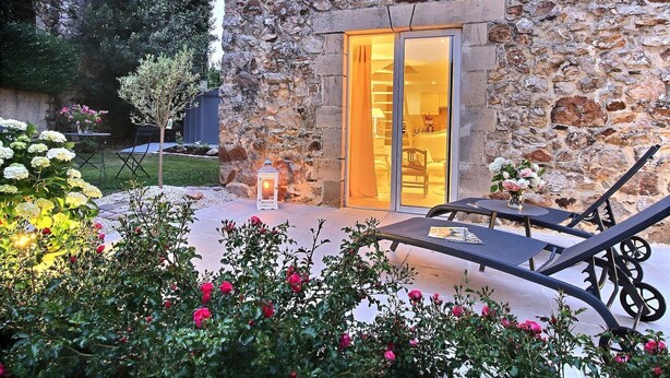 A stone building with a glass door leading to a warmly lit interior. - Le Cottage d'Etaville (Sottevast)