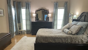 A bedroom with a bed, dresser, chair, and a mirror. - Masters Rental, 7 miles from course, 6 bedrooms, southern charm (Evans)