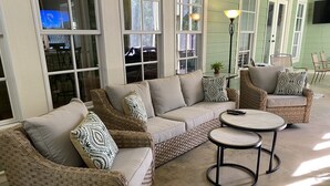 A sectional sofa with a woven frame, a round coffee table, and a wicker chair. - Masters Rental, 7 miles from course, 6 bedrooms, southern charm (Evans)