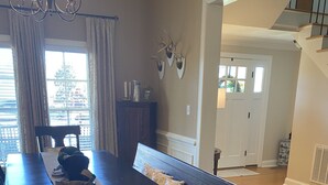 A dining area with a long table, dark wooden chairs, and a bench. There is a chandelier above the table, and a window with curtains. - Masters Rental, 7 miles from course, 6 bedrooms, southern charm (Evans)