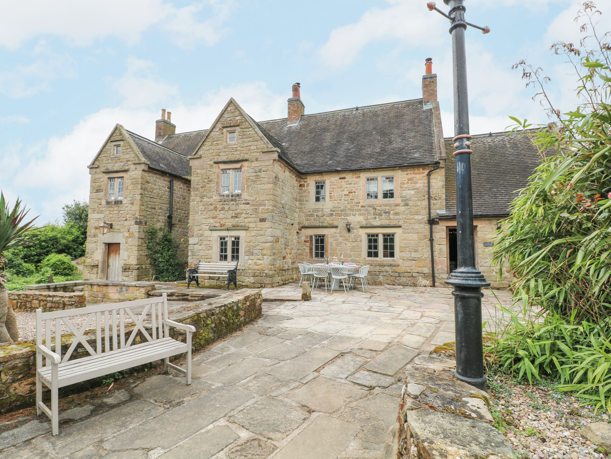 A stone building with a courtyard, a bench, and a table with chairs.