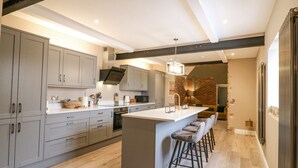 Une cuisine moderne avec des meubles gris, un îlot central doté de tabourets de bar et un luminaire suspendu.