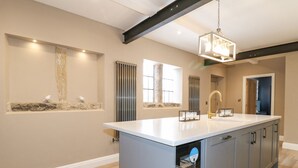 Une cuisine moderne dotée d’un îlot central, de luminaires suspendus et d’appareils électroménagers intégrés.