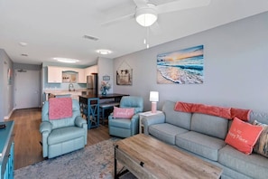 Ein modernes Wohnzimmer mit einer Couch, Sesseln, einem Couchtisch und einem Essbereich mit Tisch und Stühlen.