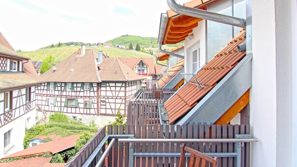 Un bâtiment traditionnel à colombages, doté d’un escalier en bois menant à un balcon.