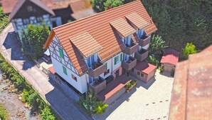 Un bâtiment à deux étages, doté d’un toit recouvert de tuiles rouges, de plusieurs balcons et d’une petite structure adjacente.
