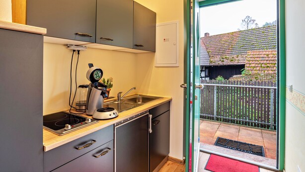 A compact kitchen with a built-in stove, a coffee maker, and a sink.