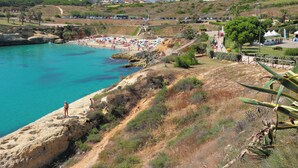 A coastal beach with clear turquoise water, rocky terrain, and a few people. - Holiday apartment with sea view (San Teodoro)