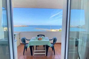 Ein Balkon mit Tisch für zwei Personen, mit Blick auf die Küste.