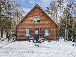 Une cabane en bois avec un porche à l’avant, une porte et des fenêtres.