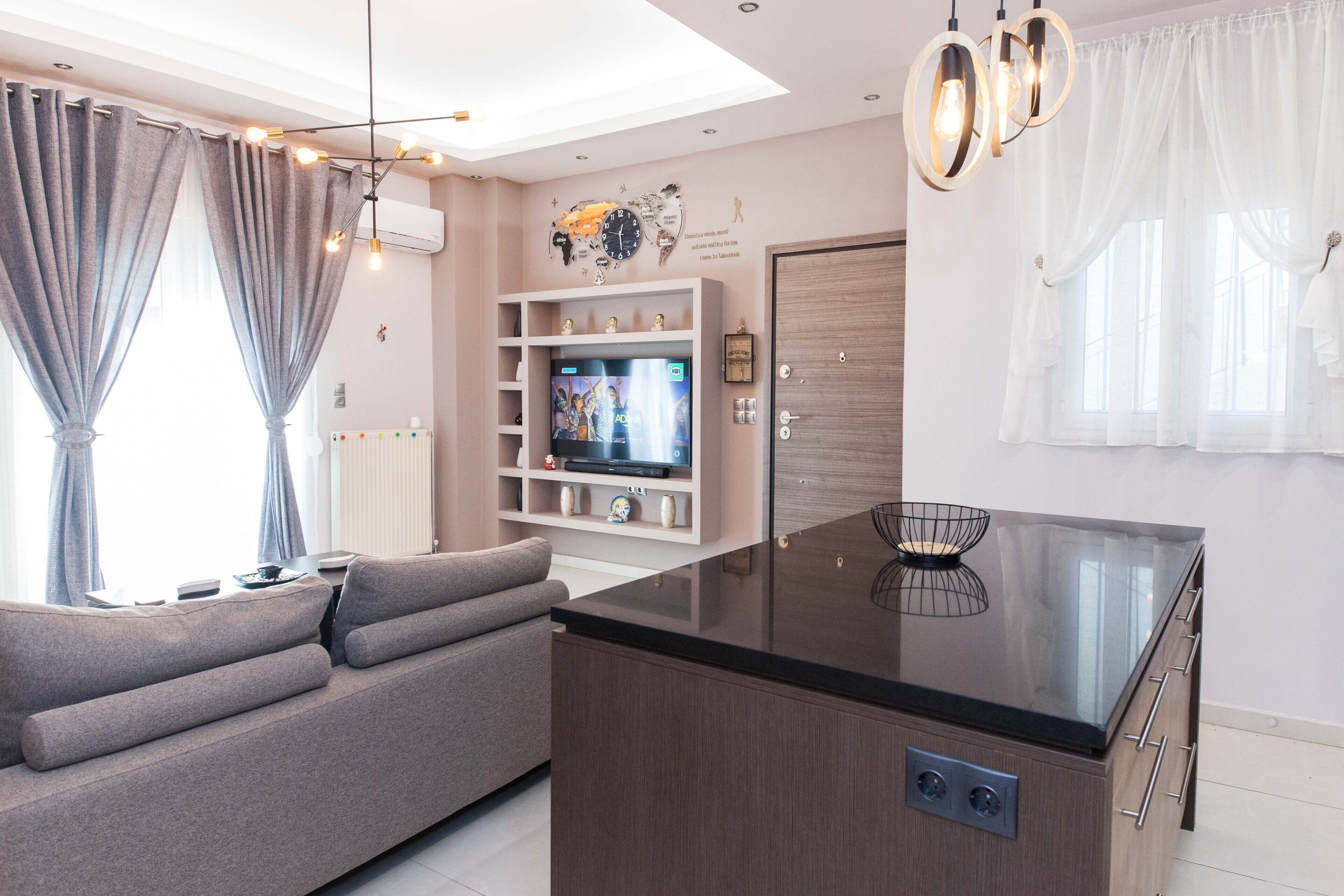 Una sala de estar moderna con un sofá, una televisión y una isla de cocina.