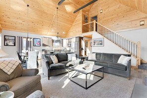 A spacious living area with a sofa, coffee table, and a staircase leading to an upper level. - Mountain Lake Retreat- Waterfront Chalet (Woodstock)